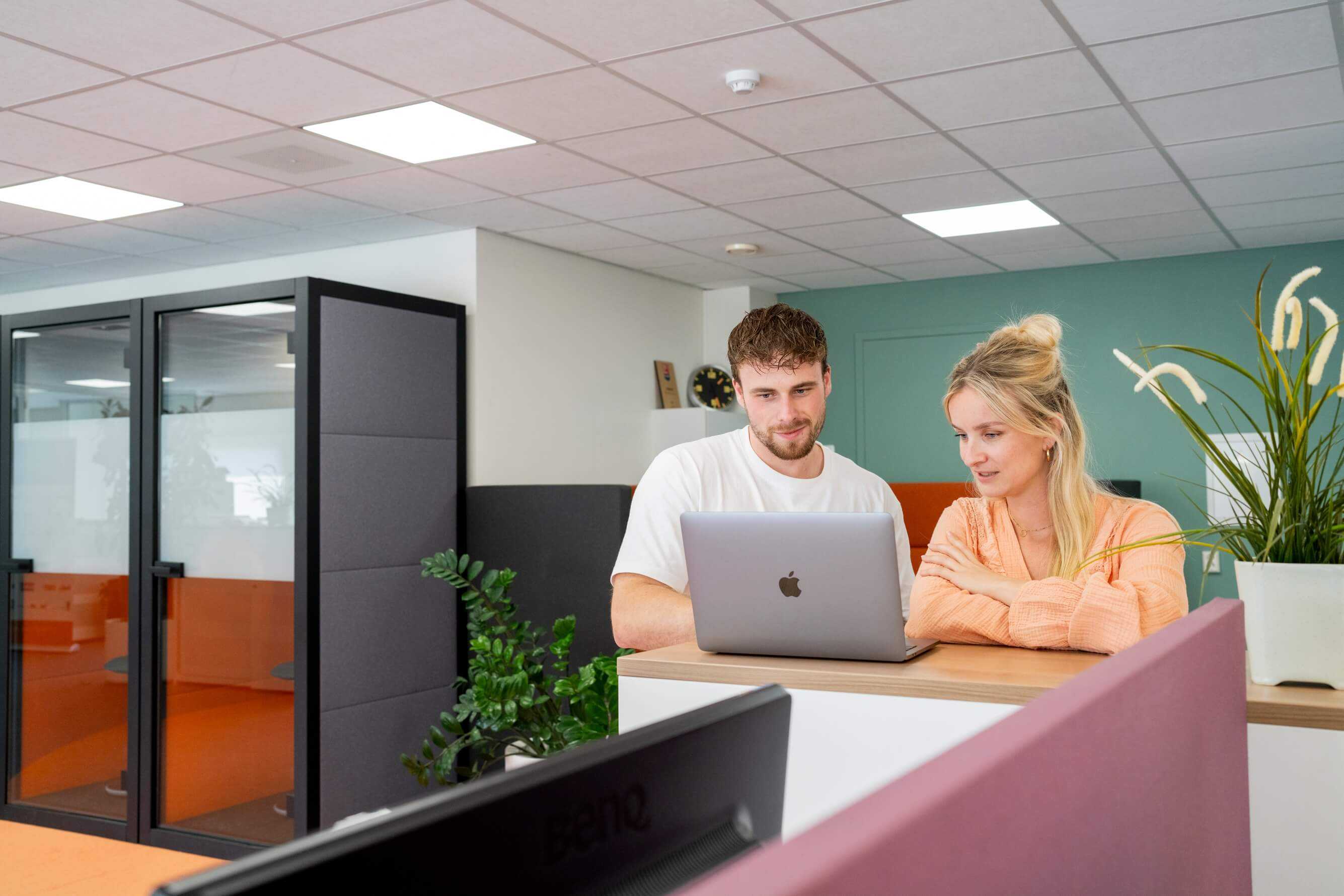 Twee collega's staan achter een laptop