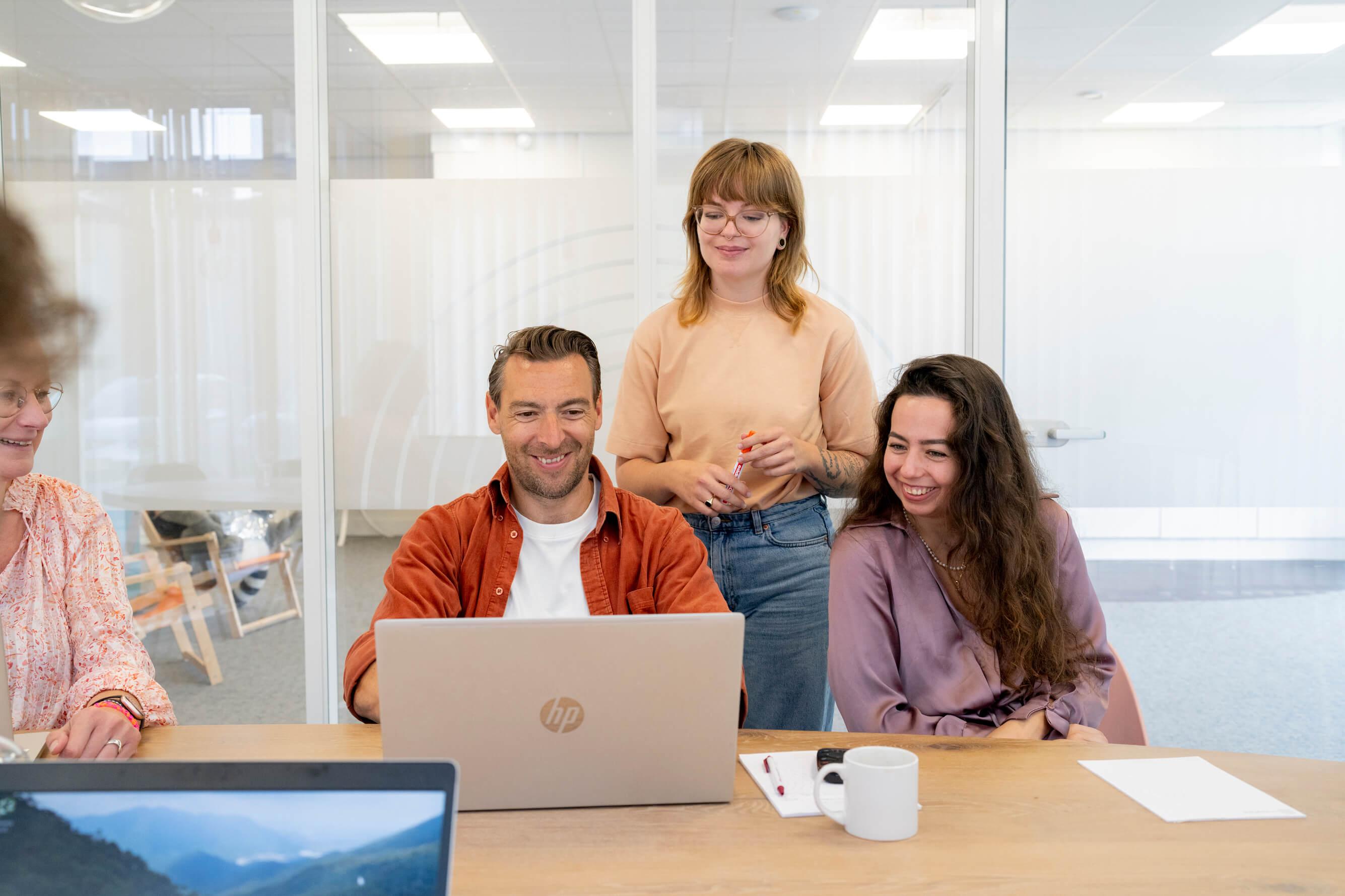 Collegas zitten achter een laptop en lachen