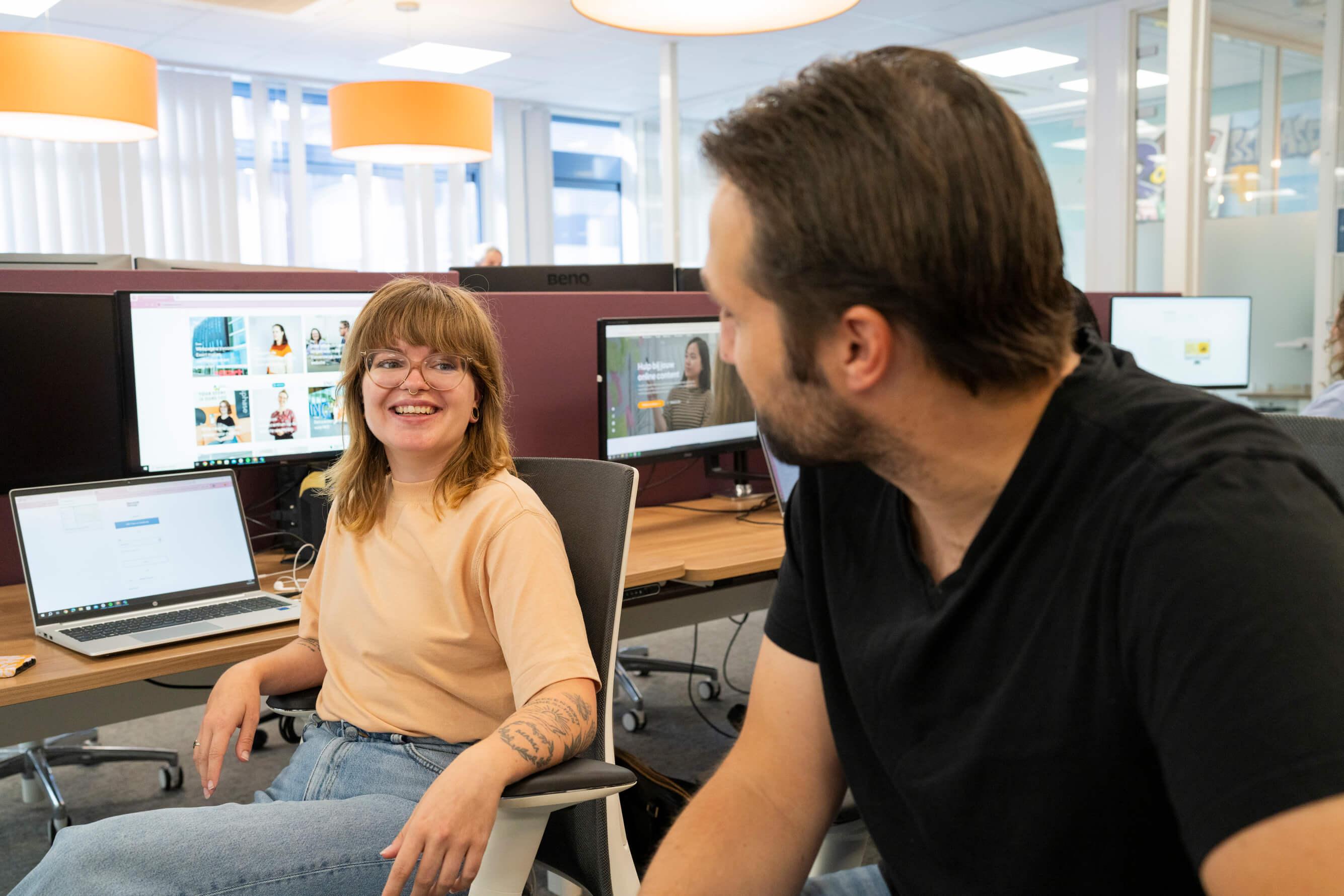 Twee collega's in gesprek aan een bureau