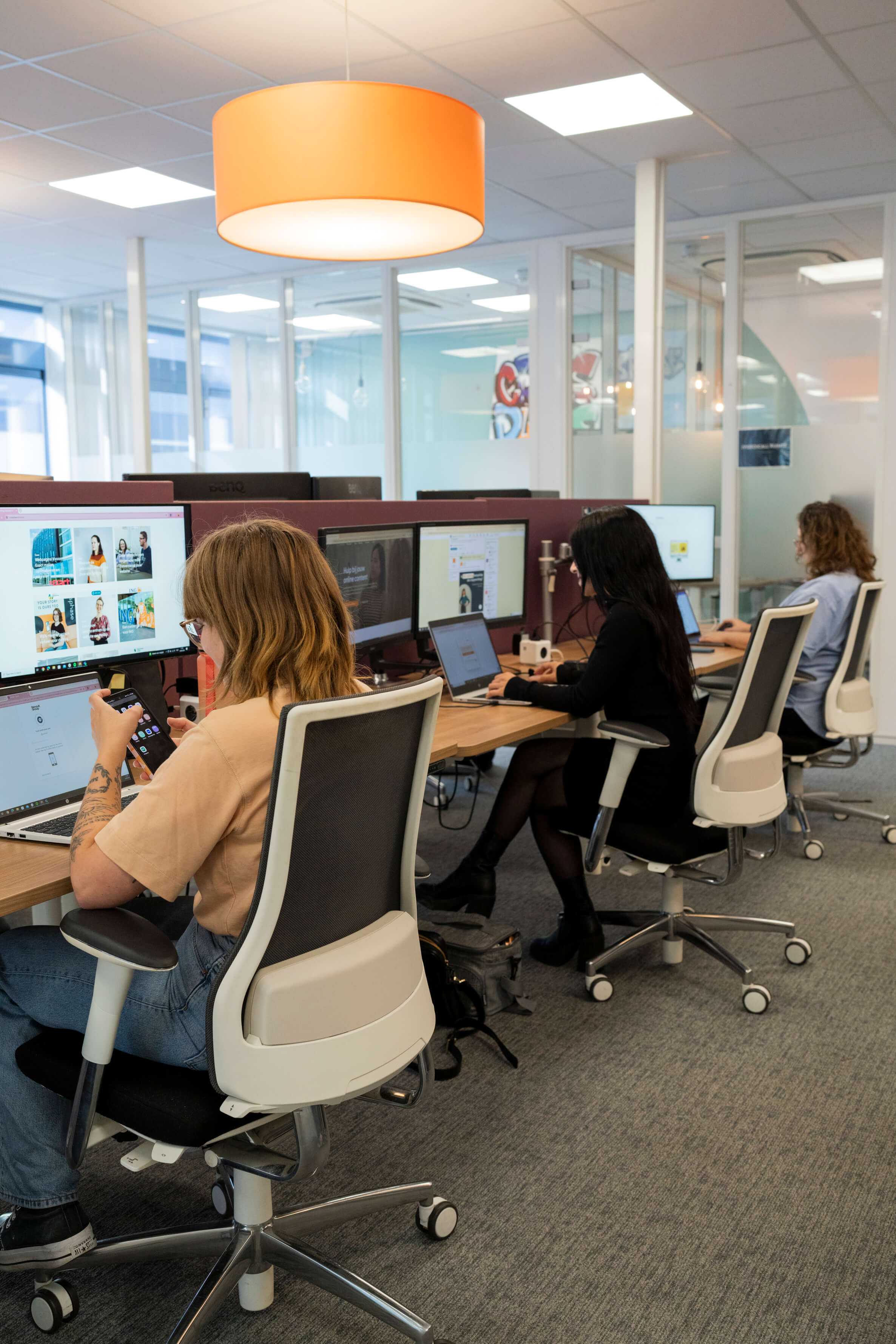 Achteraanzicht van drie werkende collega's achter een beeldscherm