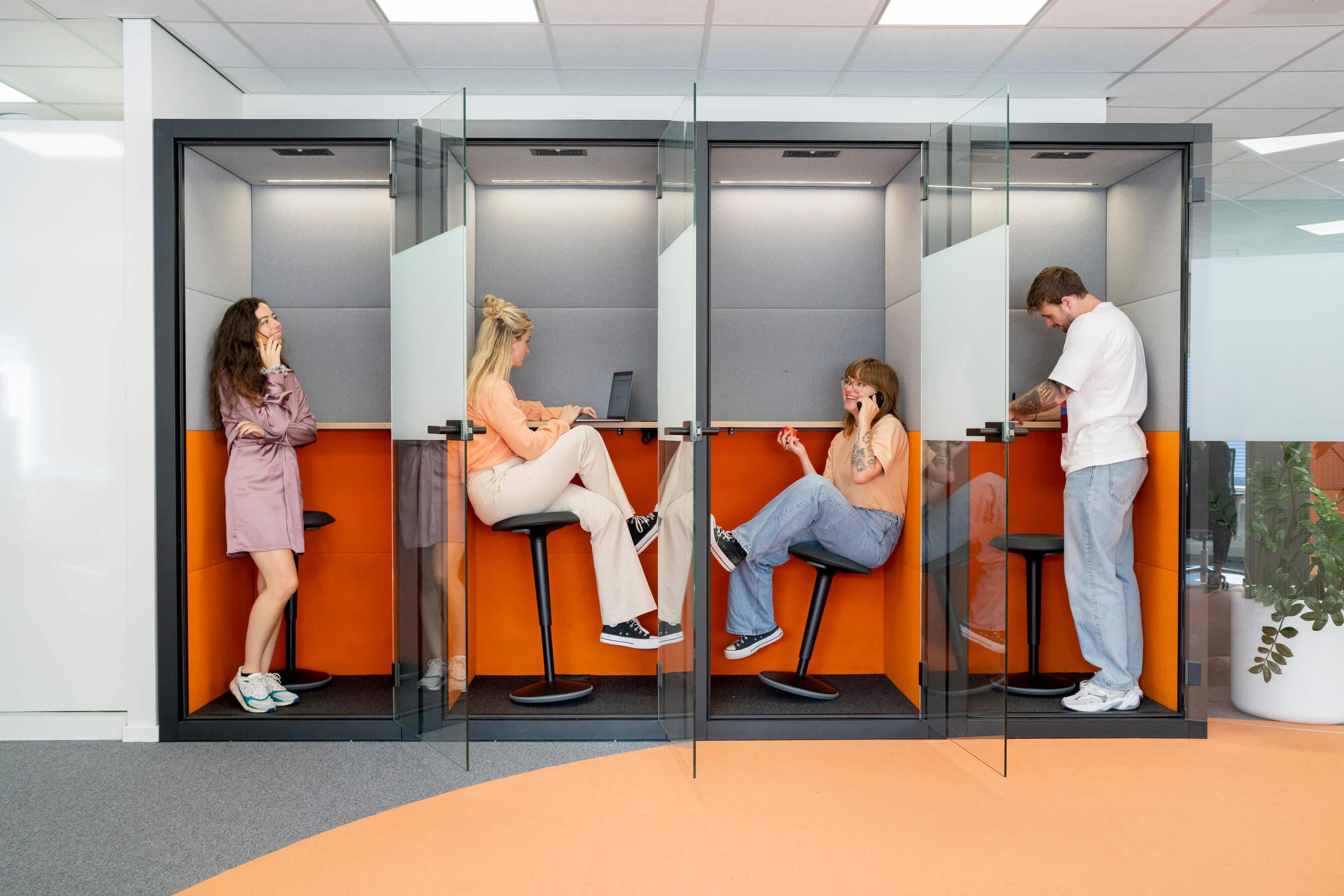 Vier collega's werken individueel in belhokjes