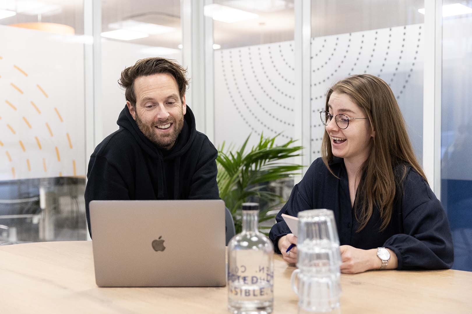 Twee mensen vrolijk achter een laptop